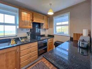 a kitchen with wooden cabinets and a black counter top at Ballygroggan Cottage - Uk48768 in Machrihanish