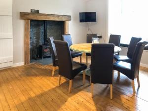 a dining room with a table and chairs and a fireplace at Ballygroggan Farmhouse - Uk35208 in Machrihanish