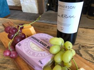 a bottle of wine and grapes on a wooden table at Ballygroggan Farmhouse - Uk35208 in Machrihanish
