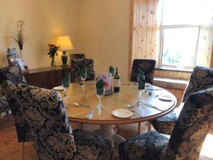 a dining room table with chairs and a table with wine glasses at Ballygroggan Farmhouse - Uk35208 in Machrihanish
