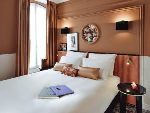 a bedroom with a large white bed with a book on it at Mercure Paris Gare De Lyon Opera Bastille in Paris +86 photos