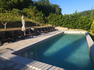 a swimming pool with chairs and an umbrella at Dorče Authentic Country House in Kojsko +76 photos