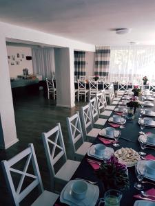 a long table with white chairs in a room at Willa Grafit in Karpacz