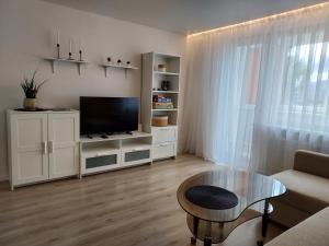 a living room with a flat screen tv and a table at Vasaros estrados apartamentai, self check-in, free parking in Klaipėda