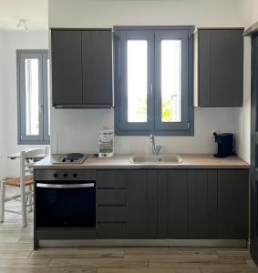 a kitchen with black cabinets and a sink at Rosalie Home - Open Sea Duo in Tinos