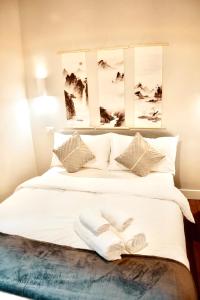 a large white bed with two white shoes on it at Zen Suite - 50m from Metro M1 - Direct to F1 Monza, Fashion Week, Duomo in Milan