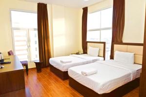 two beds in a hotel room with windows at Alpha Suites Salalah in Salalah +53 photos