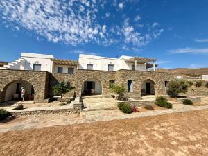 a large stone building with a person standing in front of it at Rosalie Home - Open Sea Duo in Tinos