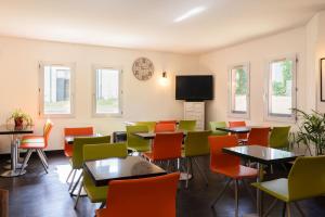a restaurant with tables and chairs and a clock on the wall at The Originals Access, Halt'Hotel, Clermont Agnetz in Agnetz