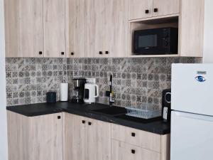 a kitchen with a black counter top and a white refrigerator at Apartment Simply 302 in Gázion