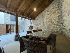 a dining room with a stone wall and a table and chairs at La Corrolada de Ana in Debodes