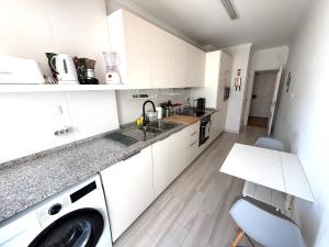 a white kitchen with a sink and a washing machine at Estoril 2 bd by the Beach in Estoril