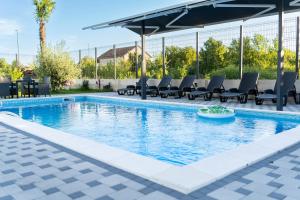 a swimming pool with chairs and a table at Villa Mali Raj in Čapljina