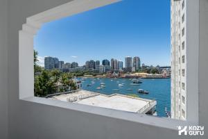 a view of a harbor from a window of a building at KozyGuru | MacMahons Point | Harbour Hideaway in Sydney