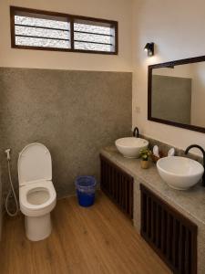 a bathroom with two sinks and a toilet and a mirror at Malcom Ocean View Retreat in Pongwe
