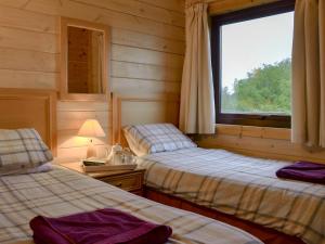 two beds in a room with a window at The Brown House in Woolfardisworthy