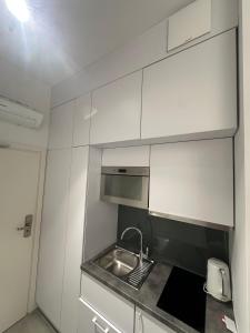 a small kitchen with a sink and a microwave at Apartament Gdański Harward lokal nr 2 in Gdańsk
