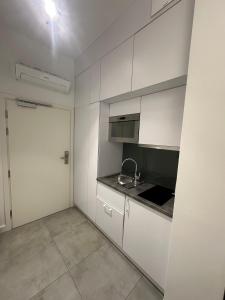 an empty kitchen with white cabinets and a sink at Apartament Gdański Harward lokal nr 2 in Gdańsk