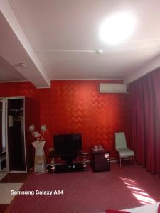 a living room with a red wall and a television at Asia Hotel in Târgu Jiu