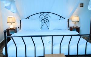 a bed with blue sheets and white pillows at Caffè Roma l'originale in Kampala