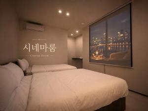 a bedroom with two beds and a large painting on the wall at Hotel Soonsu Mia in Seoul