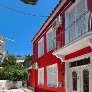 a red building with a white door and window at Plomari Rum Evi in Plomari