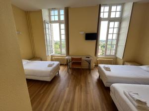 a room with two beds and a table and two windows at Hôtellerie Saint Yves in Chartres +33 photos