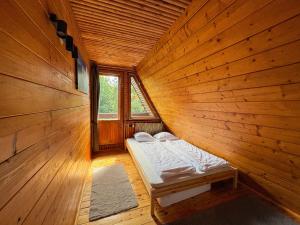 a bed in a wooden room with a window at Willa Zielony Świat in Międzybrodzie Bialskie