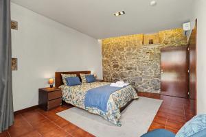 a bedroom with a bed and a stone wall at Casa de Férias Da Padroa in Braga +16 photos