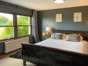 a bedroom with a large bed and two windows at Ardtur Croft in Appin