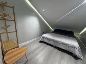 a small bedroom with a bed and a chair at Casa Attika - Modern Glasshouse with Skyline Views in Antipolo