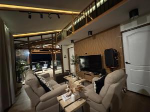 a living room with couches and a flat screen tv at Casa Attika - Modern Glasshouse with Skyline Views in Antipolo