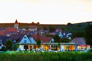 a house with lights in front of a town at Kreuz-Post Hotel-Restaurant-SPA in Vogtsburg