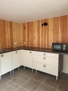 a kitchen with white cabinets and a microwave at Appartement proche Taizé Cluny in Massilly