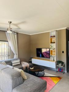 a living room with a couch and a flat screen tv at The Leafy Stay in Rundu