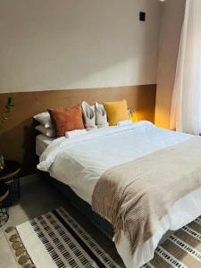 a bedroom with a large bed with white sheets and pillows at The Leafy Stay in Rundu