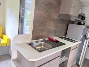 a kitchen with a sink and a stove at Bungalow Camping 4 étoiles in Messanges