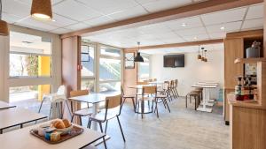a restaurant with tables and chairs and windows at Premiere Classe Valenciennes Ouest Petite Foret in Petite Forêt +16 photos