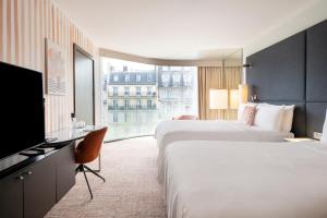 a hotel room with two beds and a flat screen tv at Renaissance Paris Arc de Triomphe Hotel in Paris