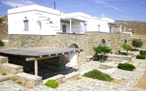 a villa with a stone wall and a building at Rosalie Home - Aegean Deck in Tinos +6 photos