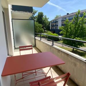 a red table and two chairs on a balcony at Studio climatisé proche du lac in Divonne-les-Bains