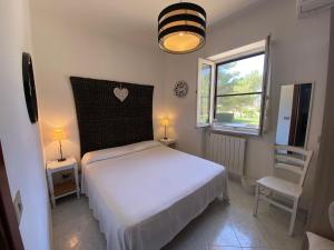 a bedroom with a white bed and a window at Anna Rita Alghero B&B in Fertilia