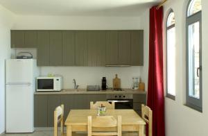 a kitchen with a table and a white refrigerator at Rosalie Home - Aegean Deck in Tinos
