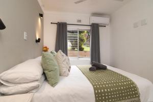 a bedroom with a bed with white sheets and a window at Ballito Beachfront Resort - 34 Chaka Chalets in Ballito +27 photos