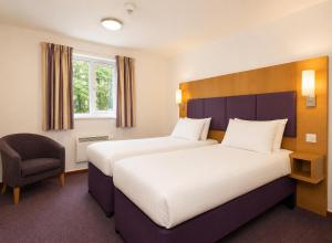 a hotel room with two beds and a chair at Middleton Inn, Manchester in Manchester