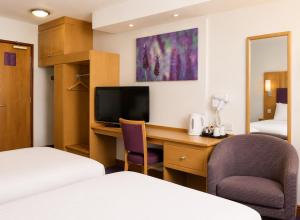 a hotel room with a desk and a bedroom at Middleton Inn, Manchester in Manchester