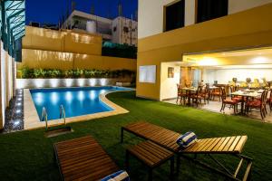 a pool with tables and chairs next to a building at Golden Lotus hotel by Trend in Aqaba