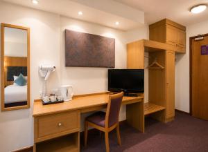 a room with a desk with a television and a bed at Middleton Inn, Manchester in Manchester
