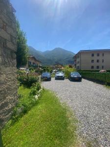 three cars parked on a gravel road next to a building at Lilly Garden Lago Lugano with private parking garden and air conditioning in Porlezza