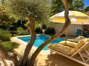 a pool with a chair and an umbrella next to a tree at Cabane la Clef des Champs au Mas des Entrages in Salon-de-Provence